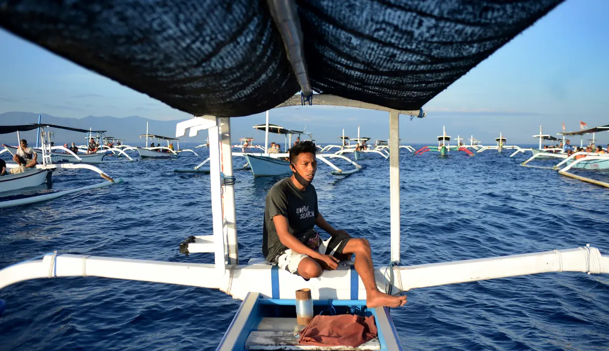 Seorang pria mengemudikan perahu saat wisata melihat lumba-lumba di perairan Pantai Lovina di Singaraja, Bali, Jumat (30/10/2020). Pantai Lovina menjadi salah satu destinasi pariwisata di Bali yang sering dikunjungi untuk menikmati matahari terbit dan lumba-lumba di laut lepas (SONNY TUMBELAKA/AFP)