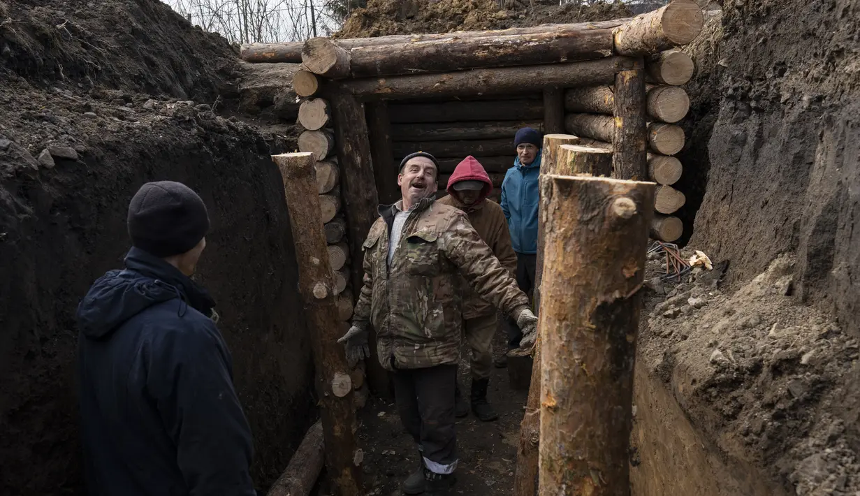 Seorang pria bercanda ketika dia bereaksi terhadap kamera saat membangun parit dengan tentara dan tetangga, di Lityn, Ukraina, Rabu, 16 Maret 2022. Invasi Rusia ke Ukraina memasuki hari ke-21. (AP Photo/Rodrigo Abd)