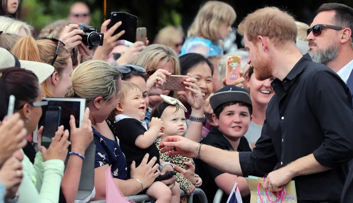 Pangeran Harry menyapa anak kecil saat berjalan di Taman Pemerintah Rotorua, Selandia Baru, Rabu (31/10). Pangeran Harry dan Meghan Markle sedang dalam tur tiga minggu di Australia, Selandia Baru, Tonga, dan Fiji. (Michael Bradley/Pool/AFP)