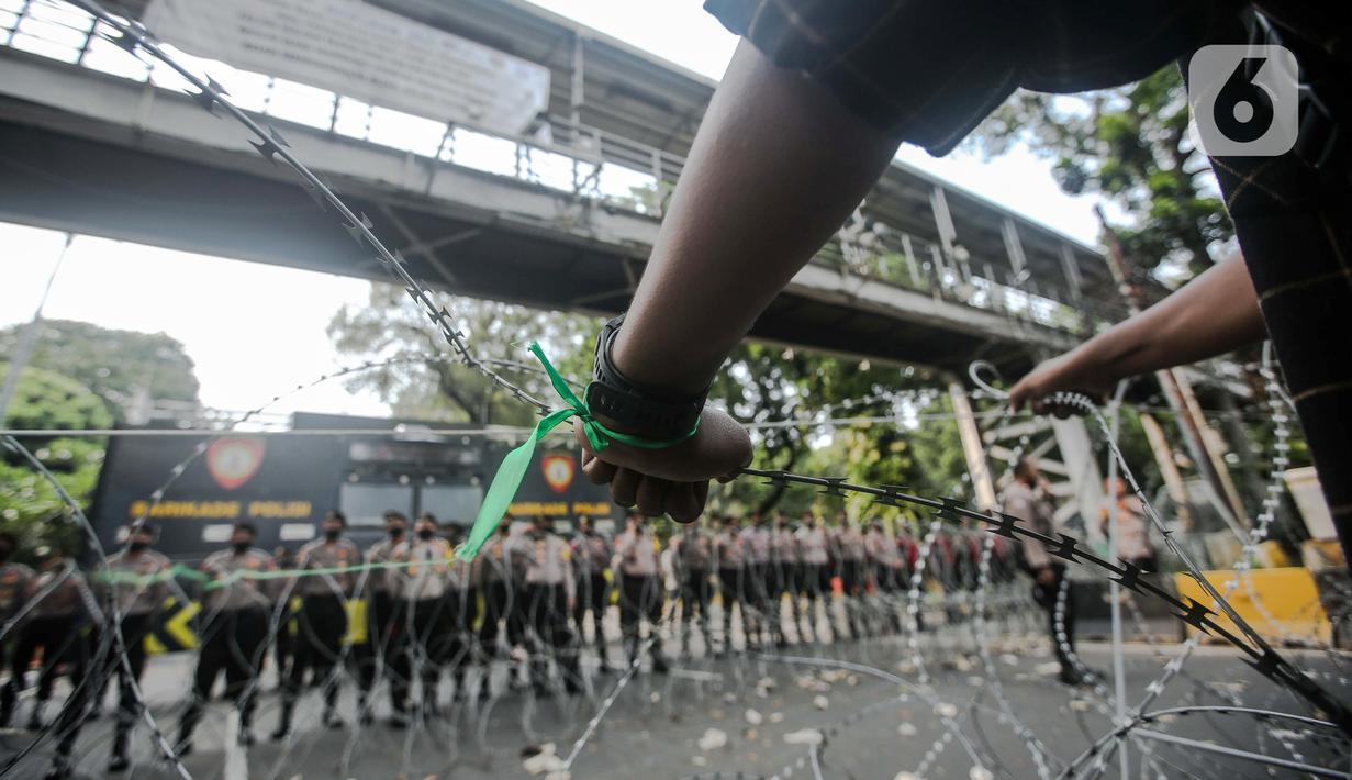 Massa yang tergabung dalam Himpunan Mahasiswa Islam (HMI) memegang kawat berduri saat menggelar aksi di depan Patung Kuda, Jakarta, Senin (29/8/2022). Mereka menolak rencana pemerintah untuk menaikkan harga BBM bersubsidi karena akan mengorbankan kondisi ekonomi rakyat, terutama masyarakat kelas menengah ke bawah dan pelaku Usaha Mikro Kecil Menengah (UMKM), yang belum sepenuhnya pulih akibat terpaan pandemi COVID-19. (Liputan6.com/Faizal Fanani)