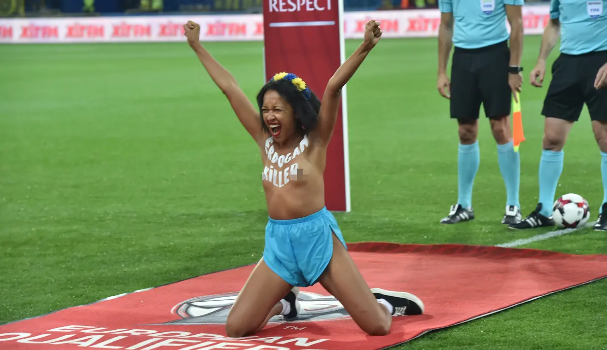 Seorang wanita bertelanjang dada berpose didalam lapangan sebelum pertandingan sepak bola kualifikasi Piala Dunia 2018 antara Ukraina dan Turki di Kharkiv (2/9). Wanita itu mengecat tubuhnya dengan tulisan "Erdogan Killer". (AFP Photo/Sergei Supinsky)