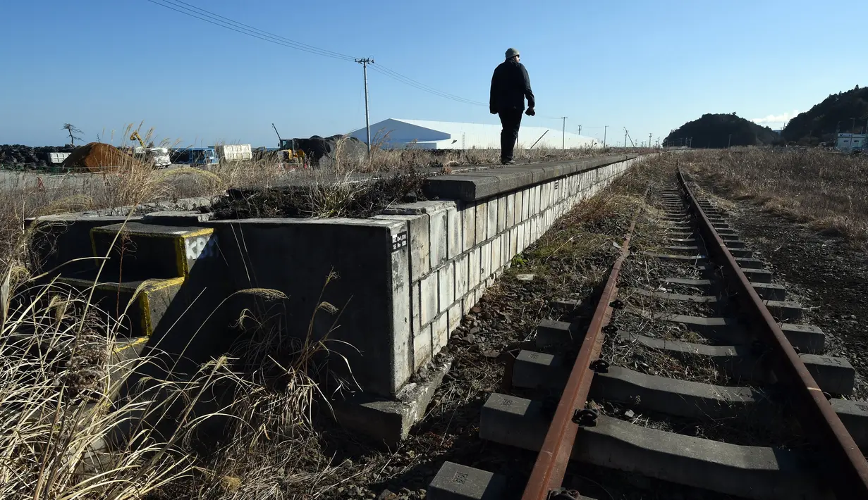 Wisatawan mengamati Stasiun Tomioka yang ditinggalkan di Namie, Prefektur Fukushima, 11 Februari 2016. Lima tahun pasca bencana nuklir yang dipicu gempa dan tsunami Jepang, banyak wisatawan yang bergabung dengan tur Fukushima (AFP PHOTO/Toru Yamanaka)
