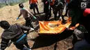 Petugas gabungan membawa kantong jenazah saat pemakaman massal di TPU Peboya Indah, Palu, Sulawesi Tengah, Rabu (3/10). Pemakaman massal tersebut memasuki hari ketiga setelah sebelumnya dilakukan di hari Senin. (Liputan6.com/Fery Pradolo)