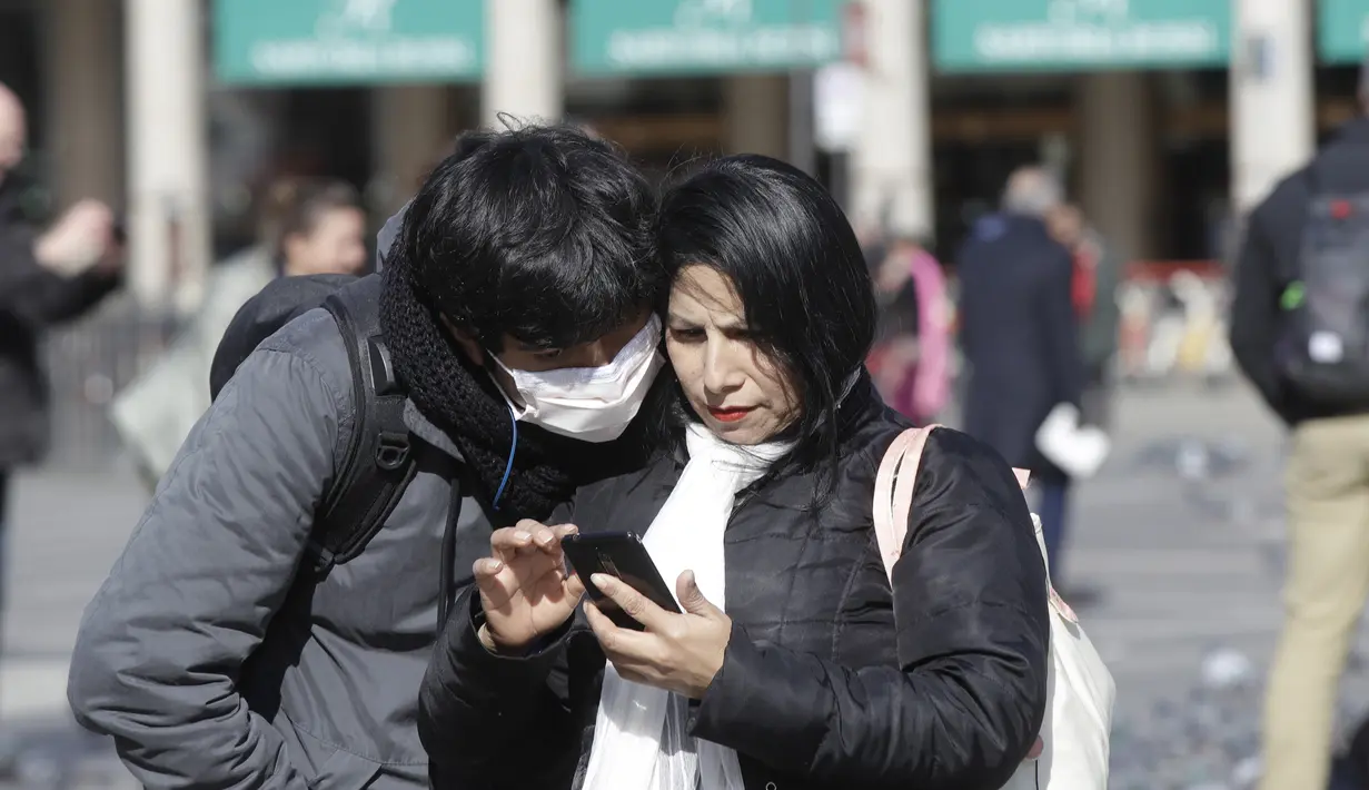 Suami istri memeriksa telepon seluler di Milan, Italia, Kamis (27/2/2020). Kementerian Kesehatan Italia, hingga Rabu 4 Maret, mencatat ada 3.089 orang yang terinfeksi Virus Corona COVID-19. Rinciannya, 2.706 kasus positif, 107 orang meninggal dunia, dan 276 orang sembuh. (AP Photo/Luca Bruno)