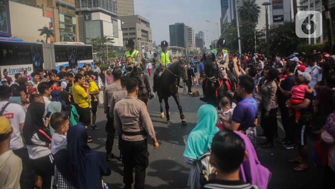 Antusiasme warga saat menyaksikan Polisi berkuda dari Direktorat Polisi Satwa Mabes Polri yang mengawasi keamanan di kawasan Bundaran HI, Jakarta, Minggu (17/11/2019). Polisi berkuda tersebut khusus ditugaskan mengawasi keamanan CFD serta memperkenalkan kepada warga. (Liputan6.com/Faizal Fanani)