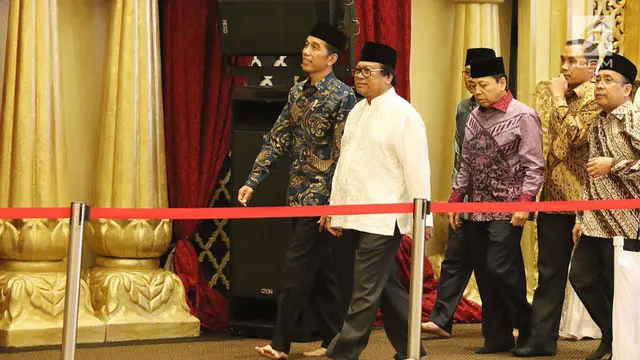 Jokowi kali ini mengenakan batik bernuansa hitam biru dengan celana panjang hitam, lengkap dengan peci hitam.