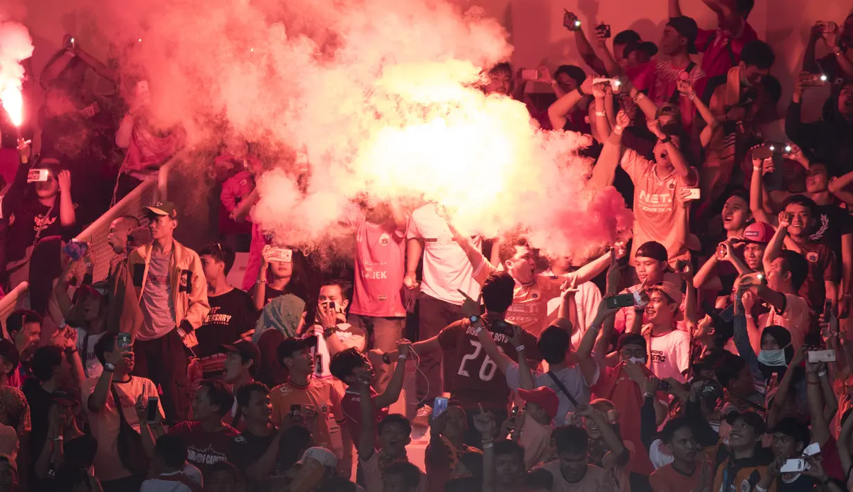 Suporter Persija Jakarta, The Jakmania, menyalakan flare usai mengalahkan Mitra Kukar pada laga Liga 1 di SUGBK, Jakarta, Minggu (9/12). Persija menang 2-1 atas Mitra. (Bola.com/Yoppy Renato)