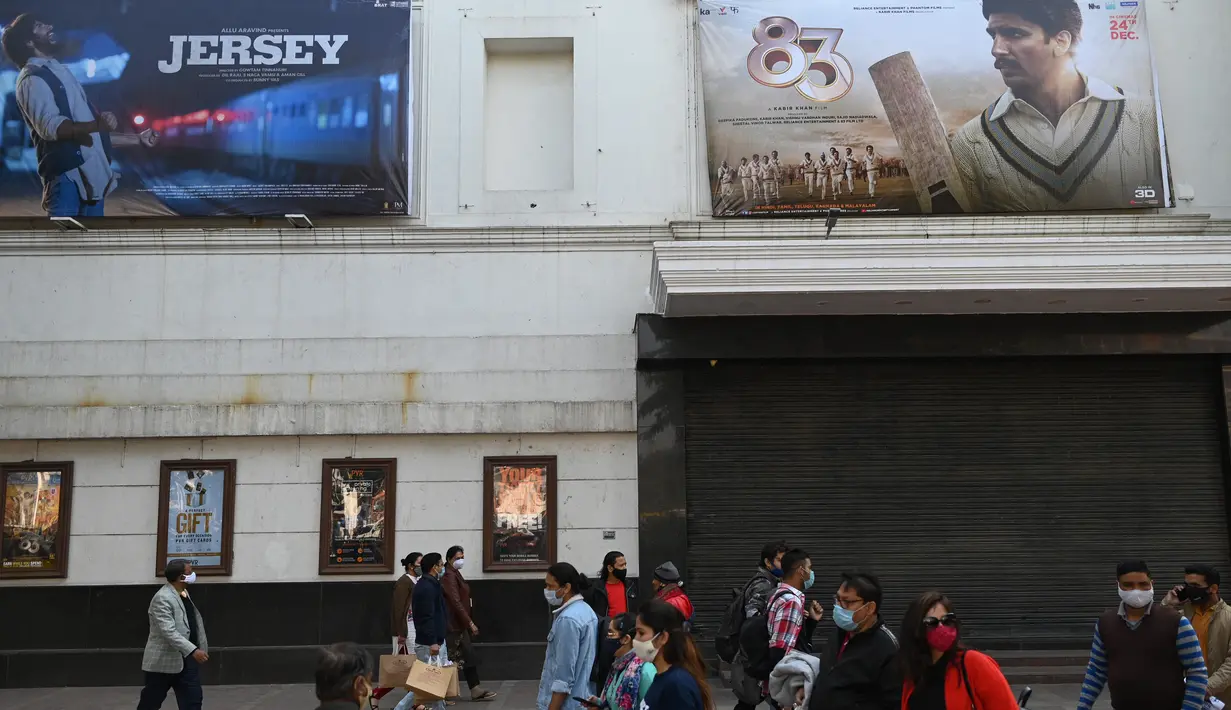 Orang-orang berjalan di sepanjang jalan di luar gedung bioskop di New Delhi (29/12/2021). Pemerintah Delhi memberlakukan pembatasan fasilitas seperti gedung bioskop, multipleks, dan gym, dan lainya untuk mengekang lonjakan virus corona Covid-19. (AFP Photo/Sajjad Hussain)