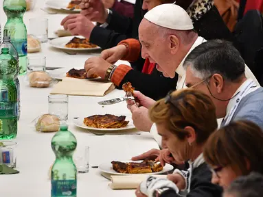 Paus Fransiskus (kanan) menyantap makan siang bersama sejumlah orang miskin di Pope Paul VI hall, Vatikan, Minggu (18/11). Makan siang bersama ratusan kaum papa, tunawisma, dan pengangguran itu memperingati Hari Orang Miskin Sedunia. (Vincenzo PINTO/AFP)