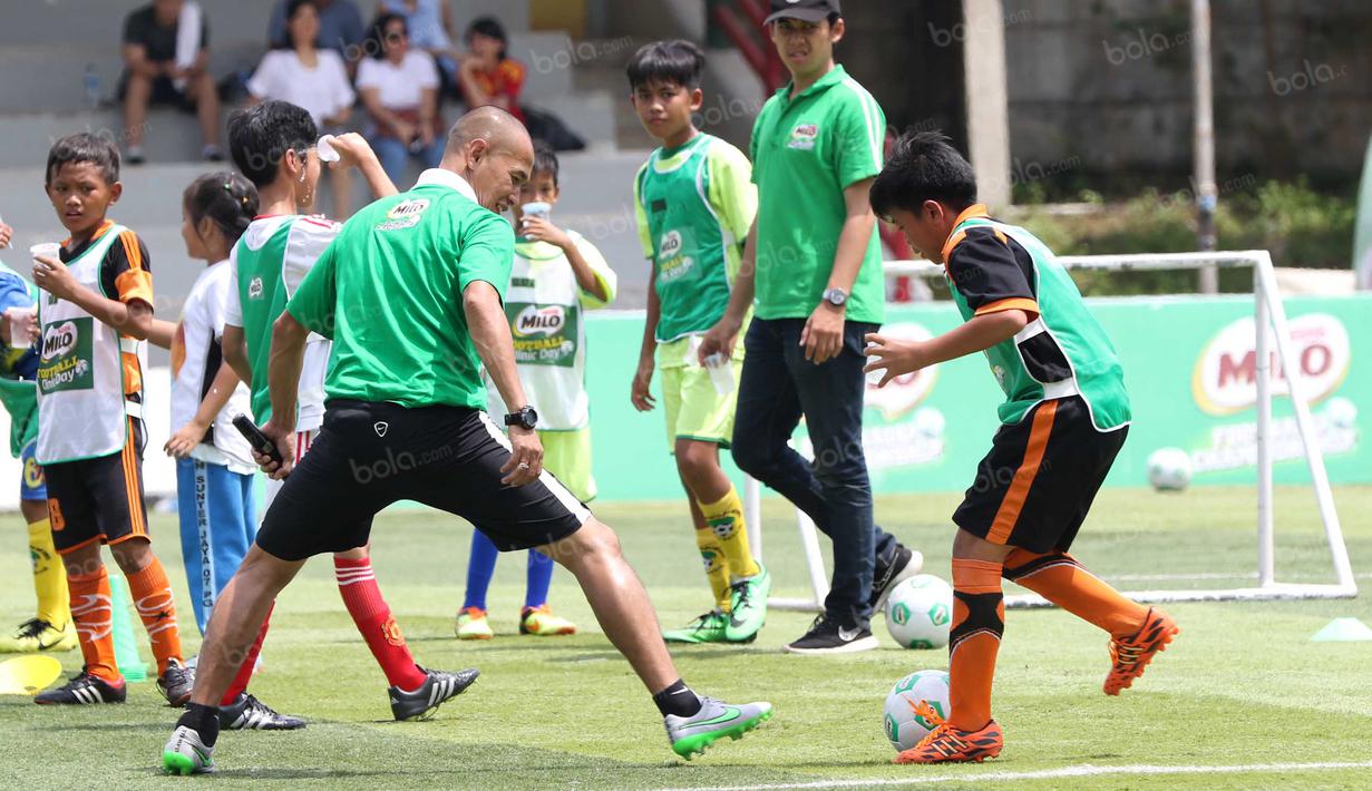 Mantan striker Timnas Indonesia, Kurniawan Dwi Yulianto, beradu skill dengan seorang anak pada acara Milo Football Clinic di Lapangan Sepak Bola Pertamina, Simprug, Jakarta, Minggu (24/4/2016). (Bola.com/Nicklas Hanoatubun)