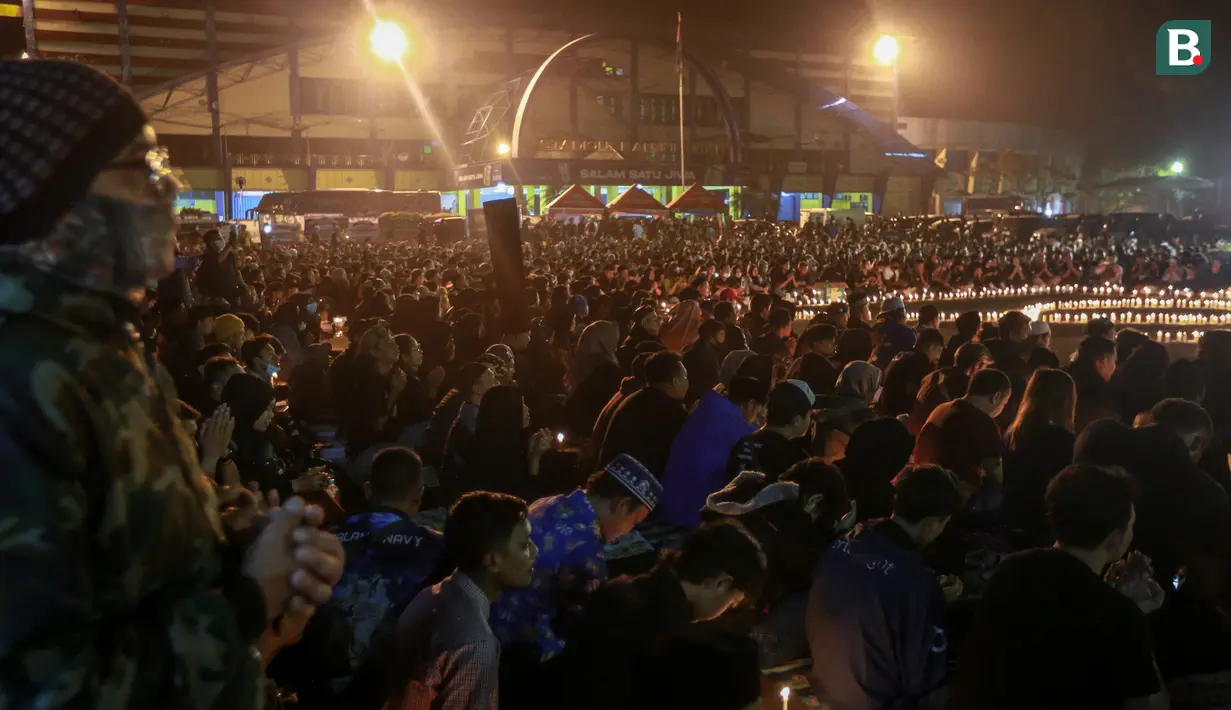 Hujan rintik-rintik membuat suasana di Stadion Kanjuruhan makin melankolis dan haru. Karena tak ada satupun yang beranjak dari tempatnya. (Bola.com/Bagaskara Lazuardi)