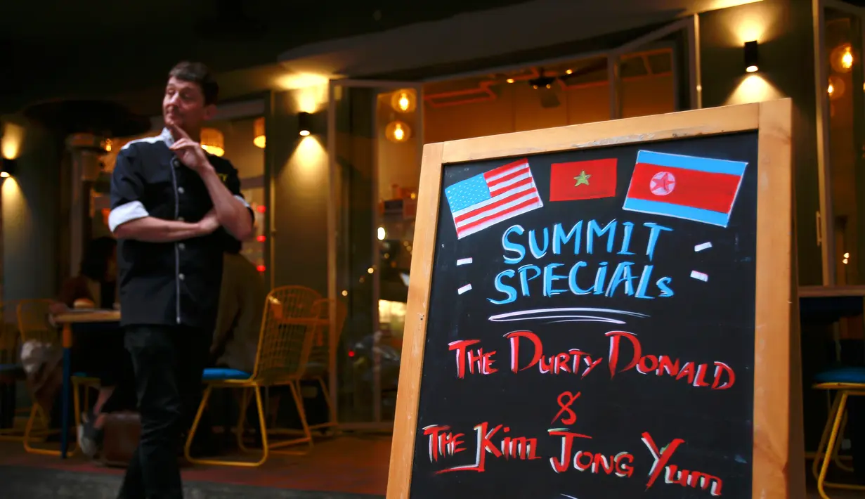 Pemilik restoran Durty Bird, Colin Kelly berdiri di sebelah menu yang menawarkan burger spesial KTT Trump-Kim di Hanoi, Vietnam, 24 Februari 2019. Dua burger didisain semirip mungkin dengan karakter Kim Jong-un dan Donald Trump. (AP/Hau Dinh)