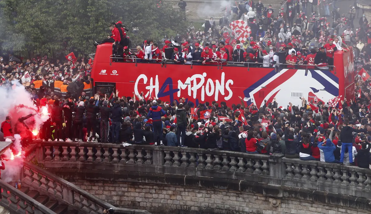 Para pemain Lille melambai kepada para penggemar dari atas bus atap terbuka saat merayakan juara Juara Ligue 1 Prancis di Lille, Prancis utara (24/5/2021). Lille tampil sebagai juara Ligue 1 Prancis musim 2020-2021, menghentikan dominasi Paris Saint-Germain. (AP Photo/Michel Spingler)