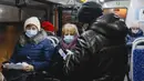 Seorang petugas (kanan) memeriksa kode QR penumpang yang membuktikan tidak adanya infeksi virus corona pada layar ponsel pintar, di dalam bus di Kazan, Senin (22/11/2021). Kazan, menjadi yang pertama di Rusia yang mulai mewajibkan bukti vaksinasi sebelumnya untuk akses transportasi umum. (AP Photo)