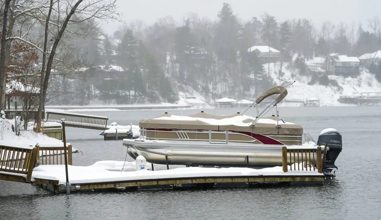 Perahu dan dermaga tertutup salju saat badai musim dingin di Danau James, Morganton, North Carolina, Amerika Serikat, 16 Januari 2022. Jarak pandang terbatas karena es, salju, dan angin menyapu area tersebut. (AP Photo/Kathy Kmonicek)