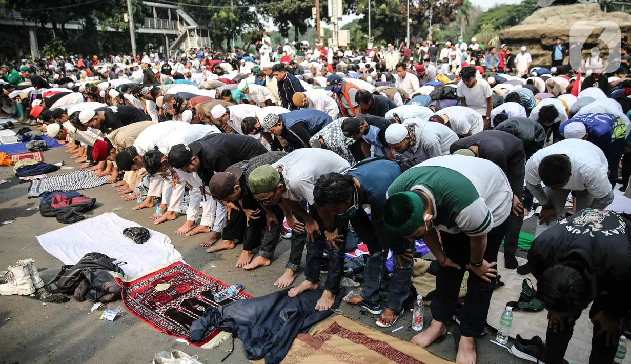 Massa aksi melaksanakan salat Ashar di sela unjuk rasa di Kawasan Patung Kuda, Jakarta, Selasa (13/10/2020). Massa aksi menolak Undang-Undang Cipta Kerja Omnibus Law tersebut salat beralaskan spanduk, kardus, hingga sajadah. (Liputan6.com/Faizal Fanani)