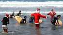 Pelatih selancar mengenakan kostum Santa Claus saat mengajar anak-anak untuk berselancar di di Pantai Kuta, Bali, Senin (10/12). Setiap tahunnya, ribuan wisatawan mendatangi Bali saat menjelang natal dan tahun baru. (AFP PHOTO / Sonny Tumbelaka)