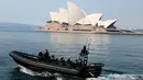 Sebuah kapal polisi berpatroli melewati Sydney Opera House (21/8/2021). Kota itu memperpanjang penguncian selama dua bulan dan memberlakukan jam malam sebagian untuk menahan wabah virus corona yang menyebar cepat. (AFP/David Gray)