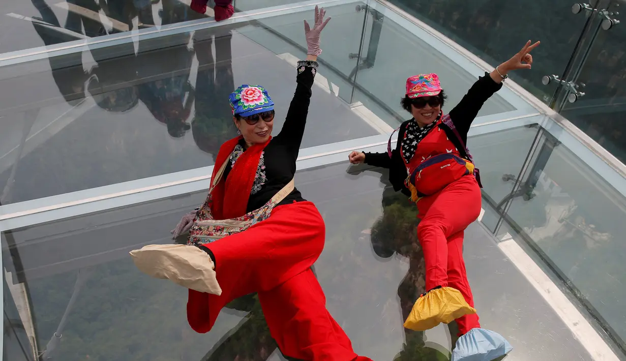 Dua turis berselfie saat mengunjungi wahana platform kaca di Shilin Gorge, Beijing, Cina, (27/5). Platform kaca ini merupakan yang terpanjang di dunia mengalahkan Grand Canyon. (REUTERS/Kim Kyung-Hoon)