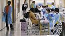 Anggota staf membantu penumpang menggunakan aplikasi ponsel untuk menjalani proses karantina pencegahan virus corona setelah mendarat di Bandara Internasional Narita di Narita, timur Tokyo, Jepang (2/12/2021). (AP Photo/Hiro Komae)