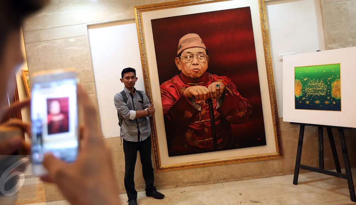 Pengunjung berfoto di dekat lukisan Presiden RI ke-4 Abdurrahman Wahid (Gusdur) saat pameran di Gedung PBNU, Jakarta, Senin (30/1). Pameran tersebut digelar dalam rangka Harlah NU ke-91. (Liputan6.com/Johan Tallo)