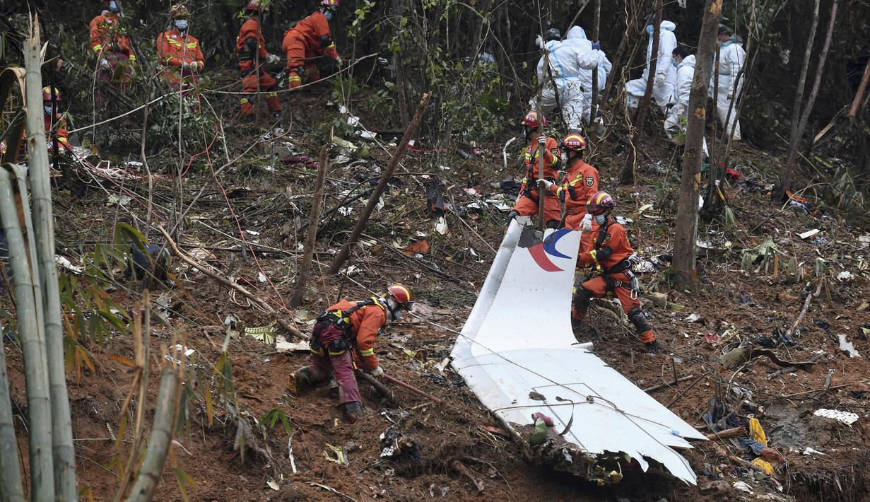 Petugas mencari kotak hitam di dekat puing-puing di lokasi kecelakaan pesawat China Eastern di Kabupaten Tengxian di Daerah Otonomi Guangxi Zhuang, China selatan (24/3/2022). Area pencarian diperluas dalam pencarian korban dan kotak hitam kedua pesawat dengan 132 orang itu. (Lu Boan/Xinhua via AP)