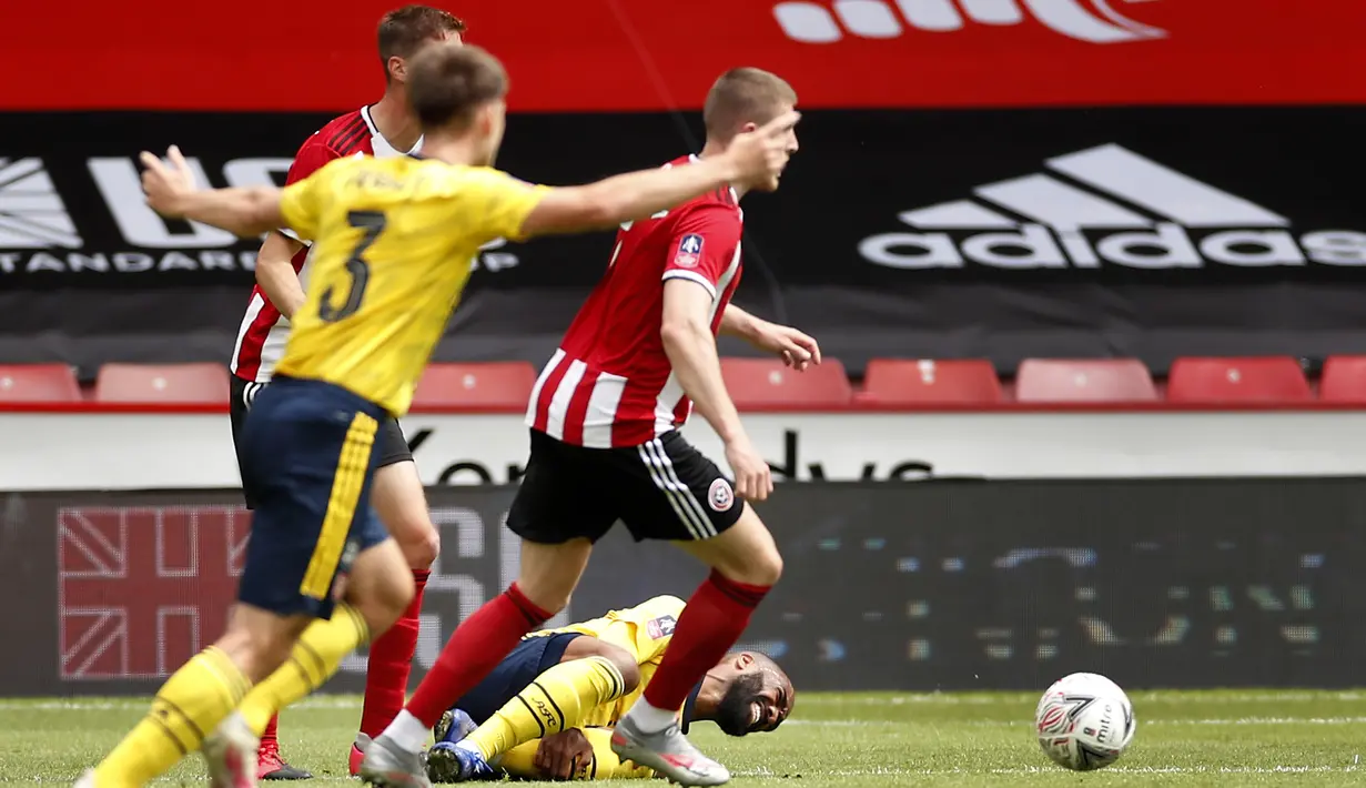 Pemain Arsenal Alexandre Lacazette (bawah) terjatuh setelah dilanggar saat menghadapi Sheffield United pada putaran keenam Piala FA di Bramall Lane, Sheffield, Inggris, Minggu (28/6/2020). Arsenal melaju ke semifinal Piala FA usai menaklukkan Sheffield United 2-1. (Andrew Boyers/Pool via AP)