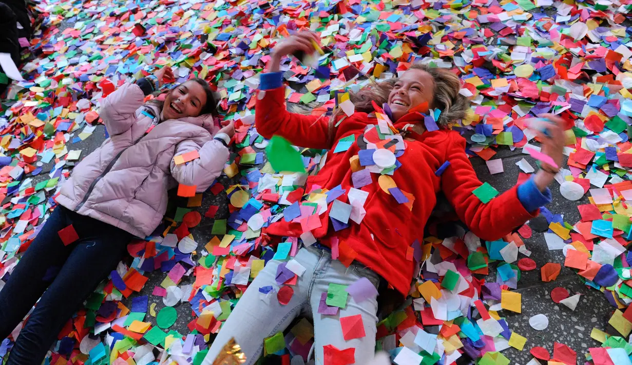 Dua orang remaja bermain confetti saat perayaan tahun baru di Times Square, New York, AS (1/1). Confetti adalah beragam potongan kertas, milar atau bahan logam yang biasanya dihamburkan dalam sebuah parade atau perayaan. (Reuters/Stephanie Keith)