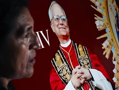 Seorang wanita berdiri di samping gambar Robert Francis Prevost, yang menjadi Paus Leo XIV pada tanggal 8 Mei 2025, di depan katedral Chiclayo di utara Lima pada hari pemilihannya sebagai paus ke-267 Gereja Katolik. (ERNESTO BENAVIDES/AFP)
