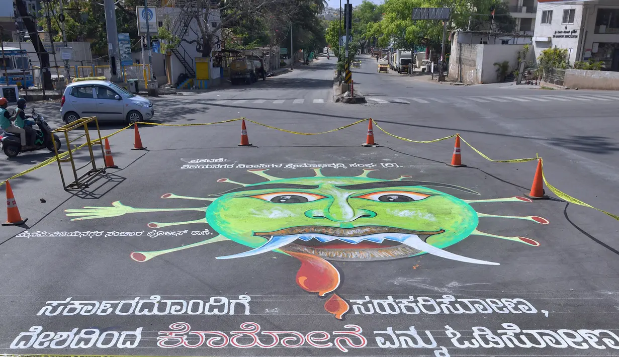 Pengendara motor melintas disamping grafiti virus  corona di persimpangan lalu lintas  di Bangalore (1/4/2020). Grafiti virus corona Covid-19 tersebut dibuat di semua persimpangan lalu lintas di Bangalore, India. (AFP/Manjunath Kiran)