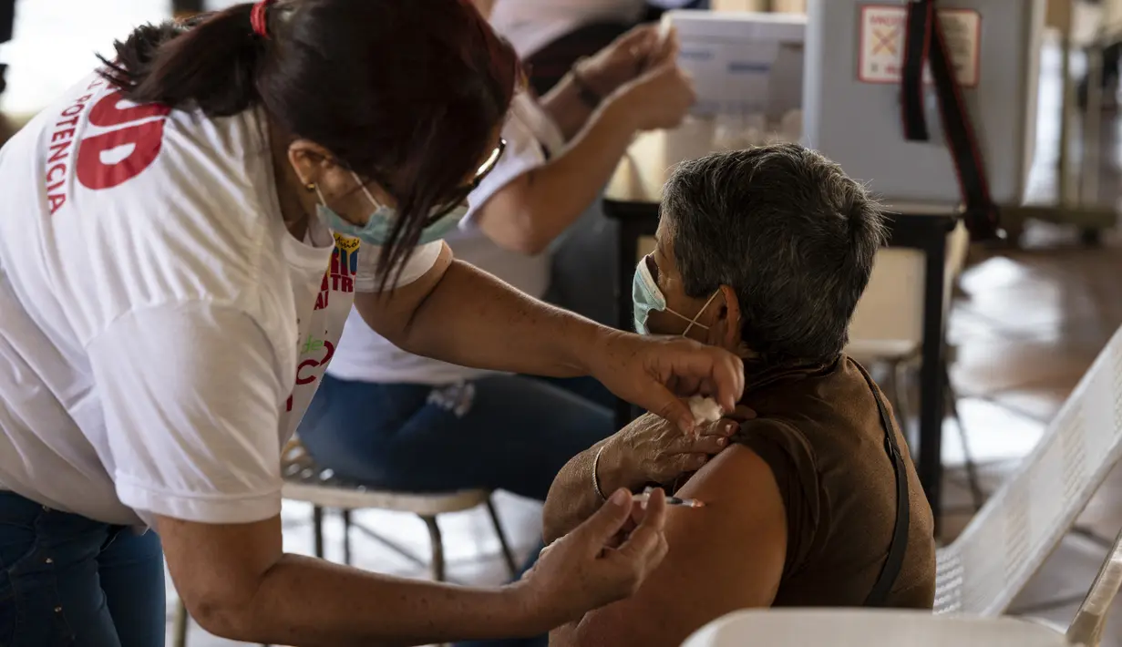 Seorang perempuan menerima dosis pertama kandidat vaksin Covid-19 Abdala buatan Kuba selama kampanye vaksinasi massal di kompleks Andres Blanco di Fuerte Tiuna, Caracas, Rabu (30/6/2021). Venezuela pada 24 Juni 2021 menandatangani kontrak untuk membeli 12 juta dosis vaksin Abdala. (Yuri CORTEZ/AFP)