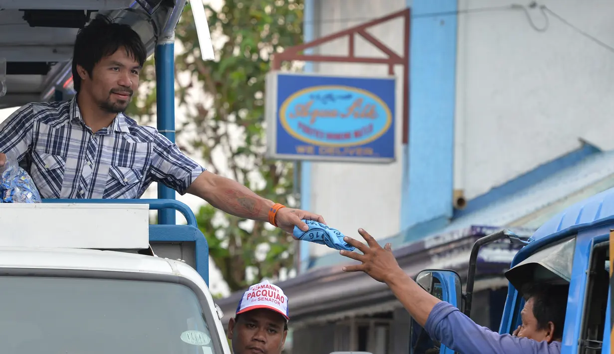 Manny Pacquiao memberikan baju ke pendukungnya selama kampanye di kota Calamba, Provinsi Laguna, selatan Manila (28/4). Manny Pacquiao menjadi salah satu politisi Filipina yang paling kuat di negaranya. (AFP PHOTO/TED aljibe)