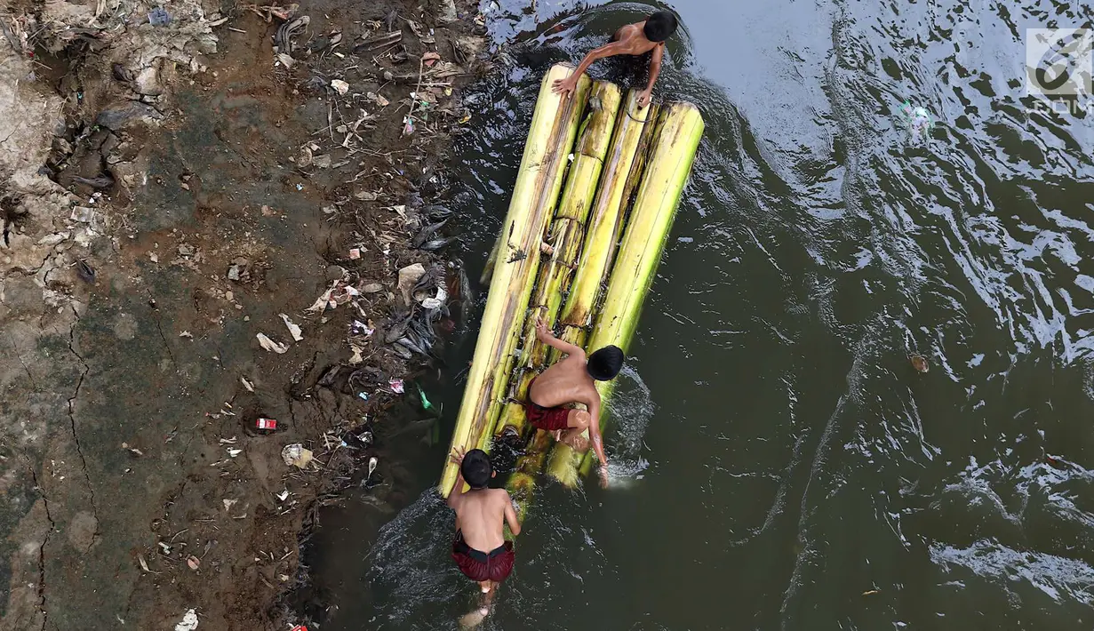 Anak-anak berenang menggunakan batang pohon pisang di bantaran Sungai Ciliwung, Jakarta, Selasa (15/5). Kurangnya pengawasan menyebabkan anak-anak tersebut bermain tidak pada tempatnya. (Liputan6.com/Immanuel Antonius)