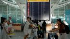 Para penumpang melihat papan elektronik yang menampilkan penerbangan yang dibatalkan di Bandara Internasional Ngurah Rai, Denpasar, Bali, Rabu 13 November 2024. (SONNY TUMBELAKA/AFP)