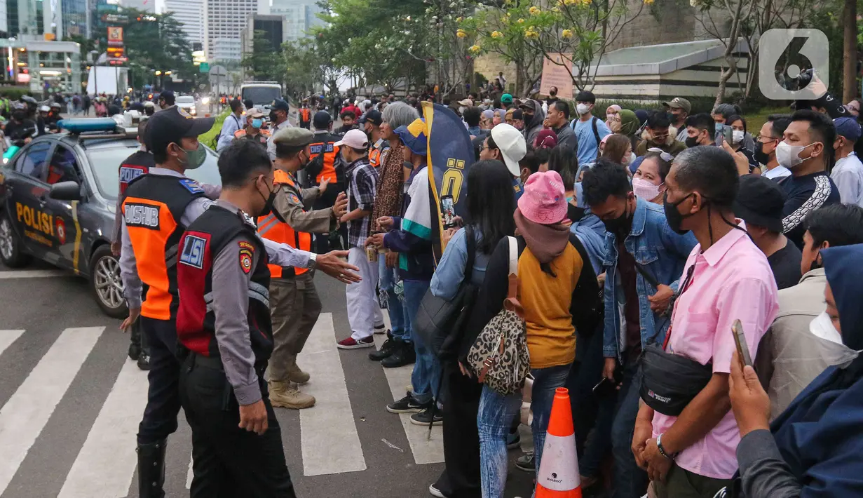Petugas membubarkan warga yang menyaksikan kegiatan Citayem Fashion Week di Stasiun BNI City, Sudirman, Jakarta Pusat, Senin (25/7/2022). Polres Jakarta Pusat bersama Dishub dan Satpol PP memberhentikan kegiatan cat walk zebra cross Citayam Fashion Week. (Liputan6.com/Herman Zakharia)