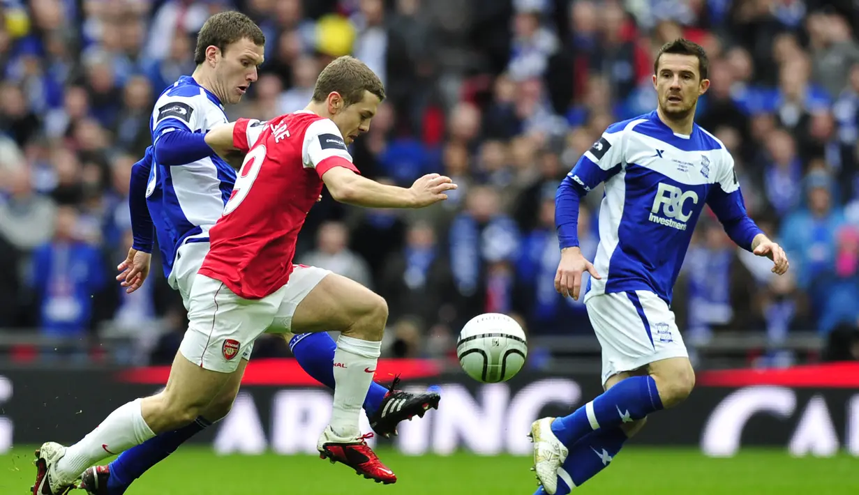Gelandang Arsenal, Jack Wilshere (tengah) menggiring bola di antara dua pemain Birmingham City pada laga final Piala Liga Inggris 2010/2011 di Wembley Stadium, London (27/2/2011). Jack Wilshere yang belum lama pensiun sebagai pemain pada Juli 2022 bersama klub Denmark, Aarhus GF tercatat pernah berseragam Arsenal selama 10 musim mulai 2008/209 hingga 2017/2018. Gelar PFA Young Player of the Year diraihnya di musim ketiganya pada 2010/2011. (AFP/Glyn Kirk)