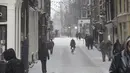 Seorang wanita mengendarai sepedanya di pusat kota Amsterdam, ketika salju dan angin kencang menyelimuti sebagian besar wilayah Belanda, Minggu (7/2/2021). Badai salju dengan suhu mencapai minus 10 derajat celsius membuat transportasi umum tidak beroperasi. (AP Photo/Peter Dejong)