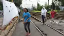 Sejumlah remaja melintasi jalur uji coba penutupan pintu perlintasan sebidang kereta api di Jalan Kebon Sereh, Jatinegara, Jakarta Timur, Senin (29/5). Uji coba penutupan dilakukan pada 26 Mei - 3 Juli 2017. (Liputan6.com/Immanuel Antonius)