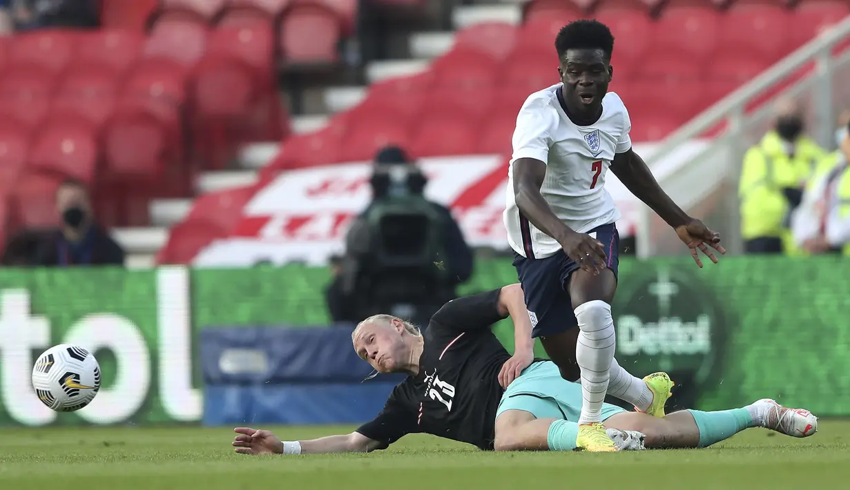 Striker Inggris, Bukayo Saka (kanan) berebut bola dengan gelandang Austria, Xaver Schlager dalam laga uji coba menjelang berlangsungnya Euro 2020 di Riverside Stadium, Middlesbrough, Rabu (2/6/2021). Inggris menang 1-0 atas Austria. (AP/Scott Heppell/Pool)