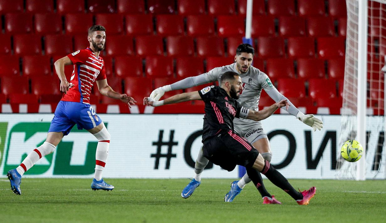 Striker Real Madrid, Karim Benzema (kanan) melepaskan tendangan yang berbuah gol keempat timnya ke gawang Granada dalam laga lanjutan Liga Spanyol 2020/2021 pekan ke-36 di Los Carmenes Stadium, Granada, Kamis (13/5/2021). Real Madrid menang 4-1 atas Granada. (AP/Fermin Rodriguez)