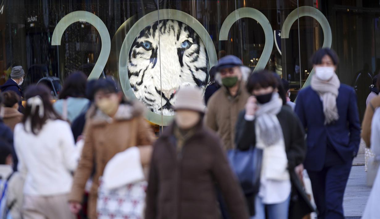 Orang-orang berjalan di sepanjang penyeberangan pejalan kaki di Tokyo (18/1/2022). Pemerintah Jepang sedang mempersiapkan pembatasan sosial di Tokyo dan wilayah lain karena varian omicron dari virus corona menginfeksi lebih banyak orang. (AP Photo/Eugene Hoshiko)