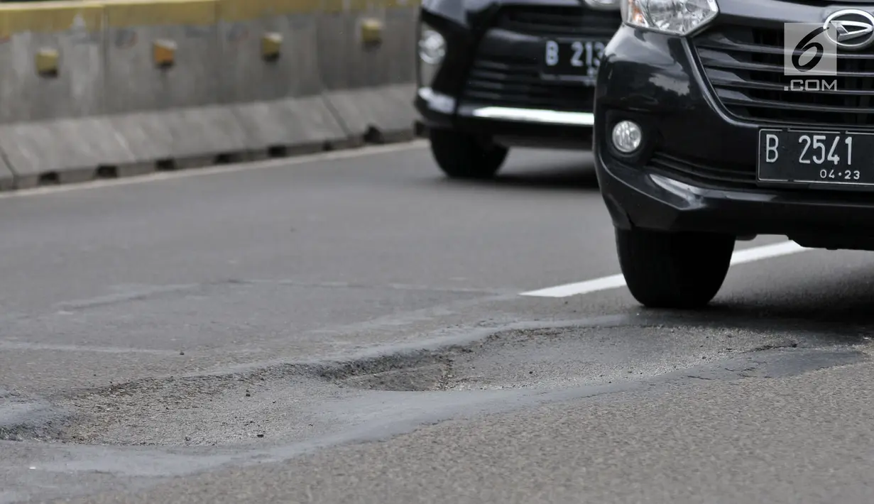 Kendaraan melintas di dekat jalan berlubang di Jalan Jenderal Sudirman, Jakarta, Senin (11/3). Minimnya perawatan dan pengawasan membuat jalan tersebut berlubang hingga kedalaman 10 sentimeter. (merdeka.com/Iqbal S. Nugroho)
