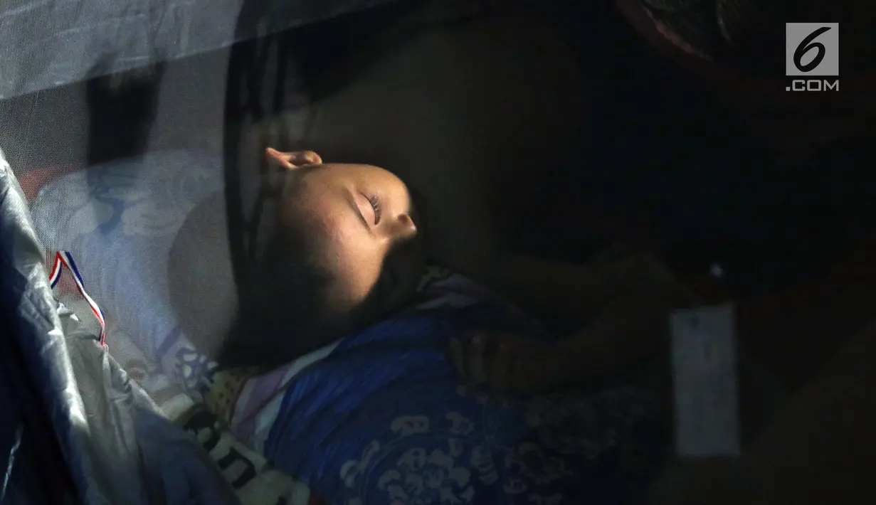 Seorang anak pencari suaka tertidur di dalam tenda di atas trotoar depan Masjid Ar-Rayan, Jalan Kebon Sirih, Jakarta, Jumat (5/7/2019). Para pencari suaka ini membangun tenda-tenda dan meminta kepastian perlindungan dari UNHCR . (Liputan6.com/Helmi Fithriansyah)