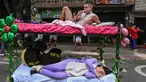 Pria dan wanita tidur di atas ranjang saat merayakan Hari Malas Sedunia di Itagui, dekat Medellin, Kolombia, Minggu (18/8/2019). Warga Kolombia membawa tempat tidur mereka ke jalanan untuk memperingati Hari Malas Sedunia. (JOAQUIN SARMIENTO/AFP)