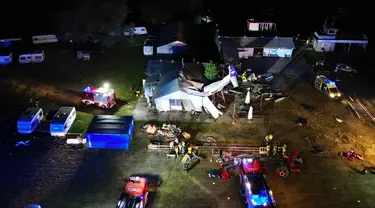 Gambar udara memperlihatkan kendaraan darurat berada dekat lokasi jatuhnya pesawat kecil Cessna 208 yang menabrak hanggar lapangan terbang di Desa Chrcynno, dekat Warsawa, Polandia, Senin (17/7/2023). Insiden tersebut lantas menewaskan lima orang. (Damien SIMONART/AFP)
