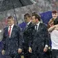 Presiden FIFA Gianni Infantino menutupi kepalanya dengan tangan sementara Presiden Rusia, Vladimir Putin dilindungi payung saat hujan turun selama penyerahan medali dan trofi Piala Dunia 2018 di Stadion Luzhniki, Minggu (15/7). (AP/Matthias Schrader)