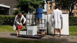 Ilmuwan Belgia, Marjolein Vanoppen dan Sebastiaan Derese menunjukkan penggunaan mesin yang bisa mengubah air seni menjadi air diminum dan menjadi pupuk dengan bantuan energi matahari di University of Ghent, Belgia, Selasa (26/7). (REUTERS/Francois Lenoir)