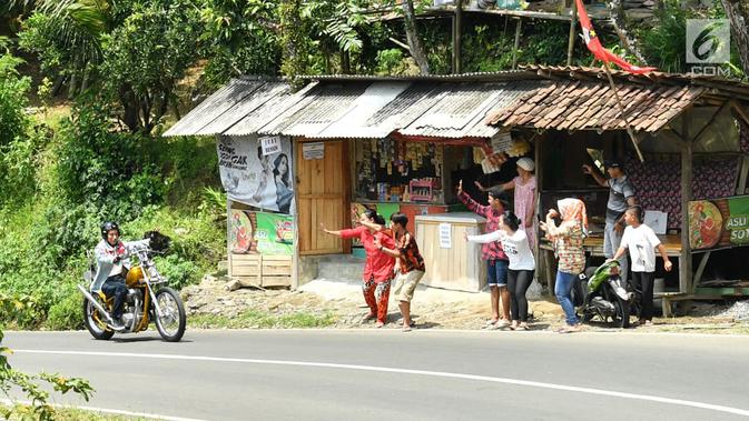 Warga menyapa Presiden Jokowi saat mengendarai motor di Sukabumi, Jawa Barat, Minggu (8/4). Blusukan terkait program Kementerian PUPR dan Kementerian Desa, Pembangunan Daerah Tertinggal dan Transmigrasi. (Liputan6.com/Pool/Biro Pers Setpres)