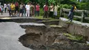 Sejumlah warga India mengamati sebuah jembatan yang hancur akibat hujan deras di Desa Toribari, pinggiran Siliguri, Kamis (21/7). Hujan deras yang terus menerus turun di India dalam 48 jam terakhir menyebabkan banjir dan tanah longsor (DIPTENDU Dutta/AFP)