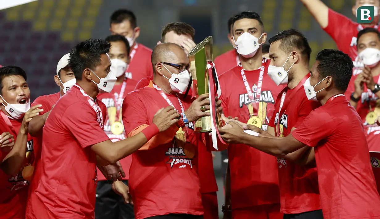 Kapten Persija Jakarta, Andritany Ardhiyasa, memberikan trofi kepada pelatih, Sudirman, usai menjuarai Piala Menpora 2021 di Stadion Manahan, Solo, Minggu (25/4/2021). (Bola.com/M Iqbal Ichsan)